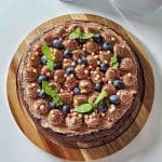 En hasselnötsbrownie med Nutellafrosting dekorerad med blåbär och mintblad.