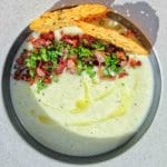 En skål med potatis- och purjolökssoppa toppad med bacon och krutonger.